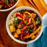 Two bowls of vegetable stir-fry with tofu and rice