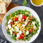 Bowl of Italian tuna salad with arugula, tomatoes and corn