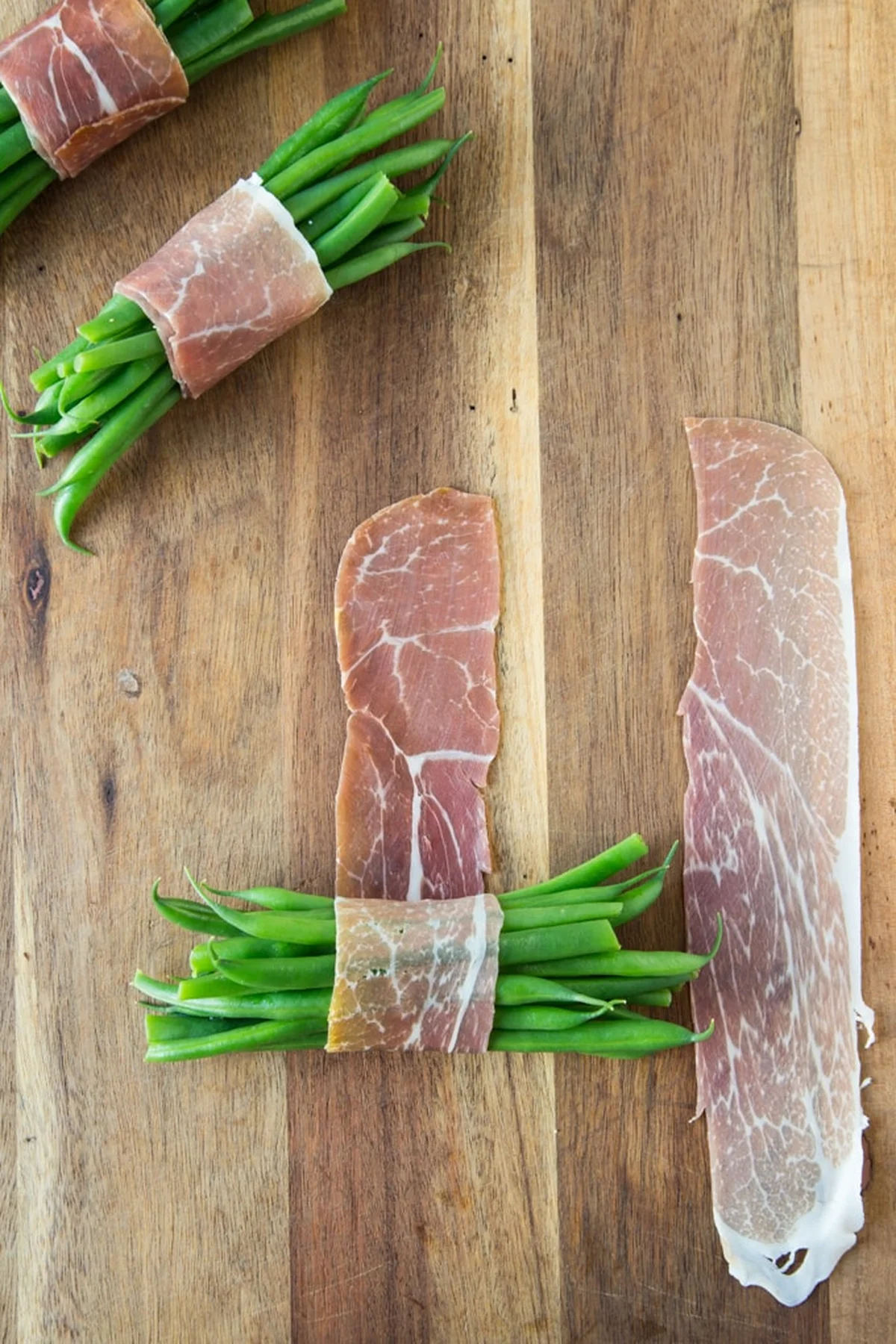 Wrapping blanched green beans with a prosciutto slice