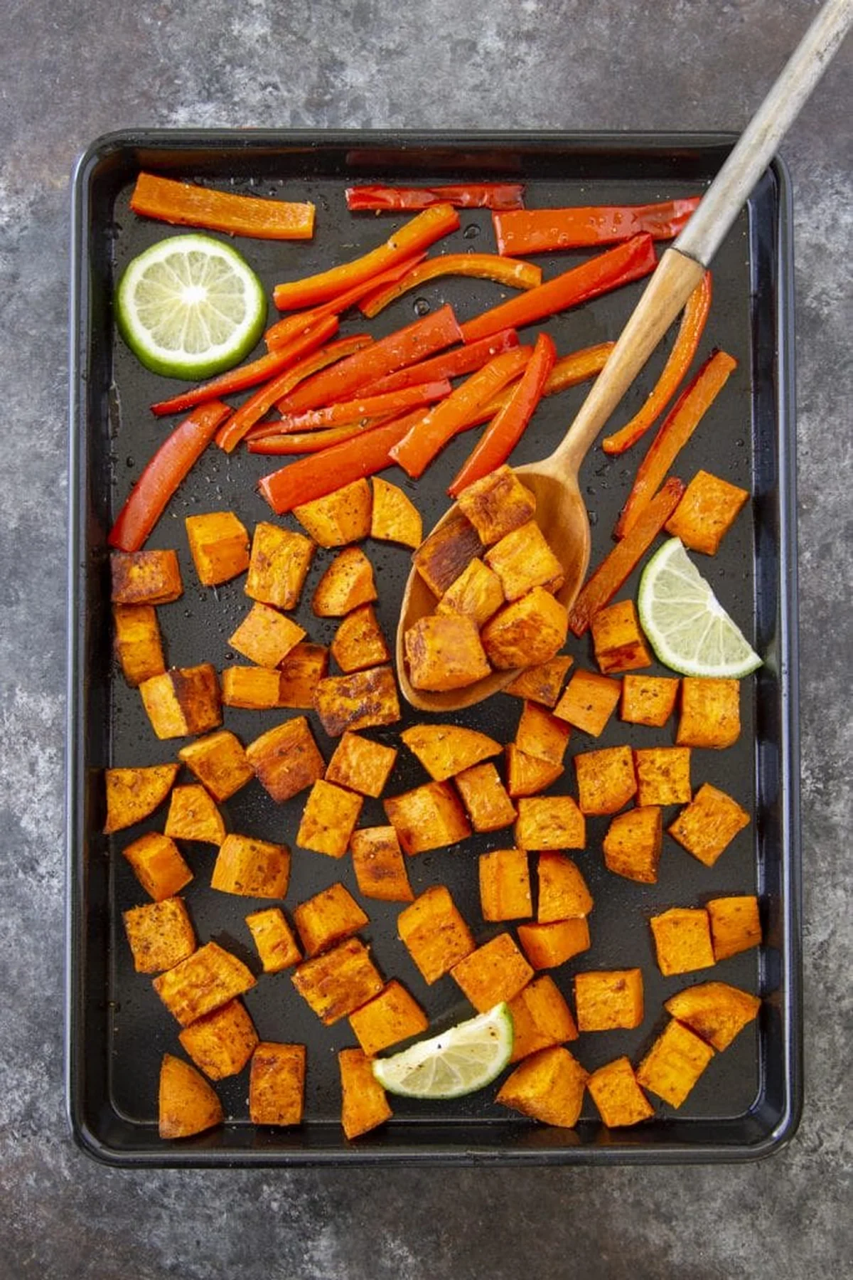 Roasted spiced sweet potatoes and bell peppers on baking sheet