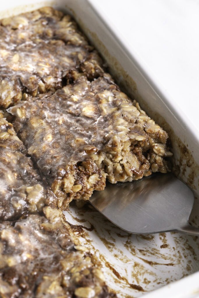 Spatula lifting a square of baked oatmeal from the pan