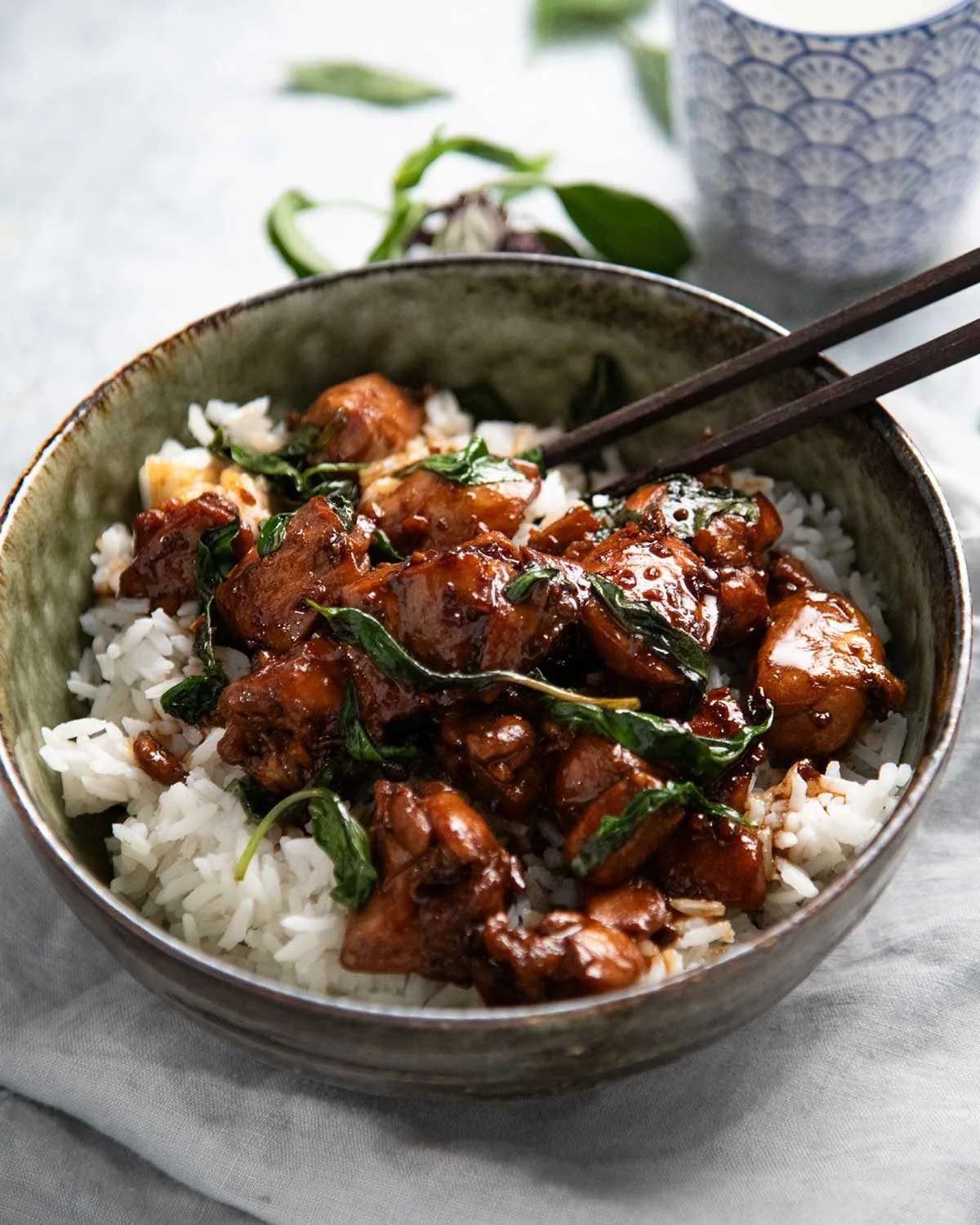 Bowl of glossy Three Cup Chicken with Thai basil over white rice