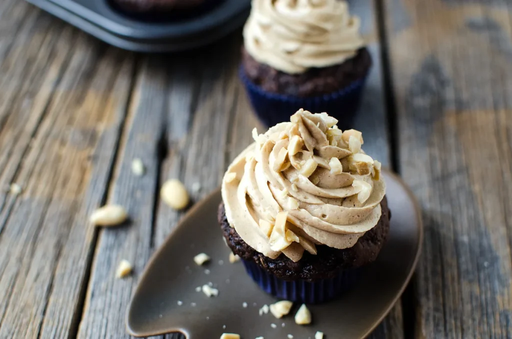 Chocolate zucchini cupcake with peanut butter frosting on wooden table