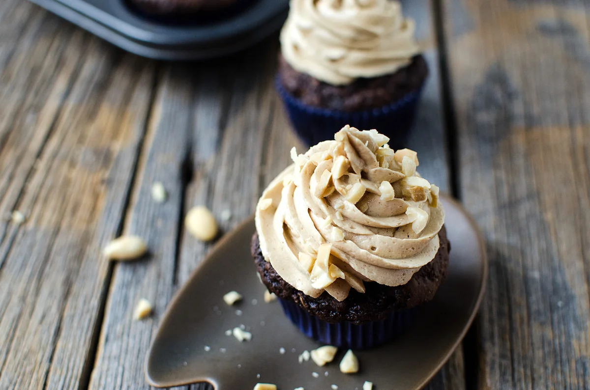 Chocolate zucchini cupcake with peanut butter frosting on wooden table