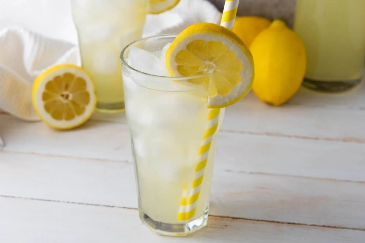 Tall glass of homemade lemonade with ice and lemon slice