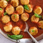 Baked chickpea meatballs in tomato sauce with fresh basil, top-down