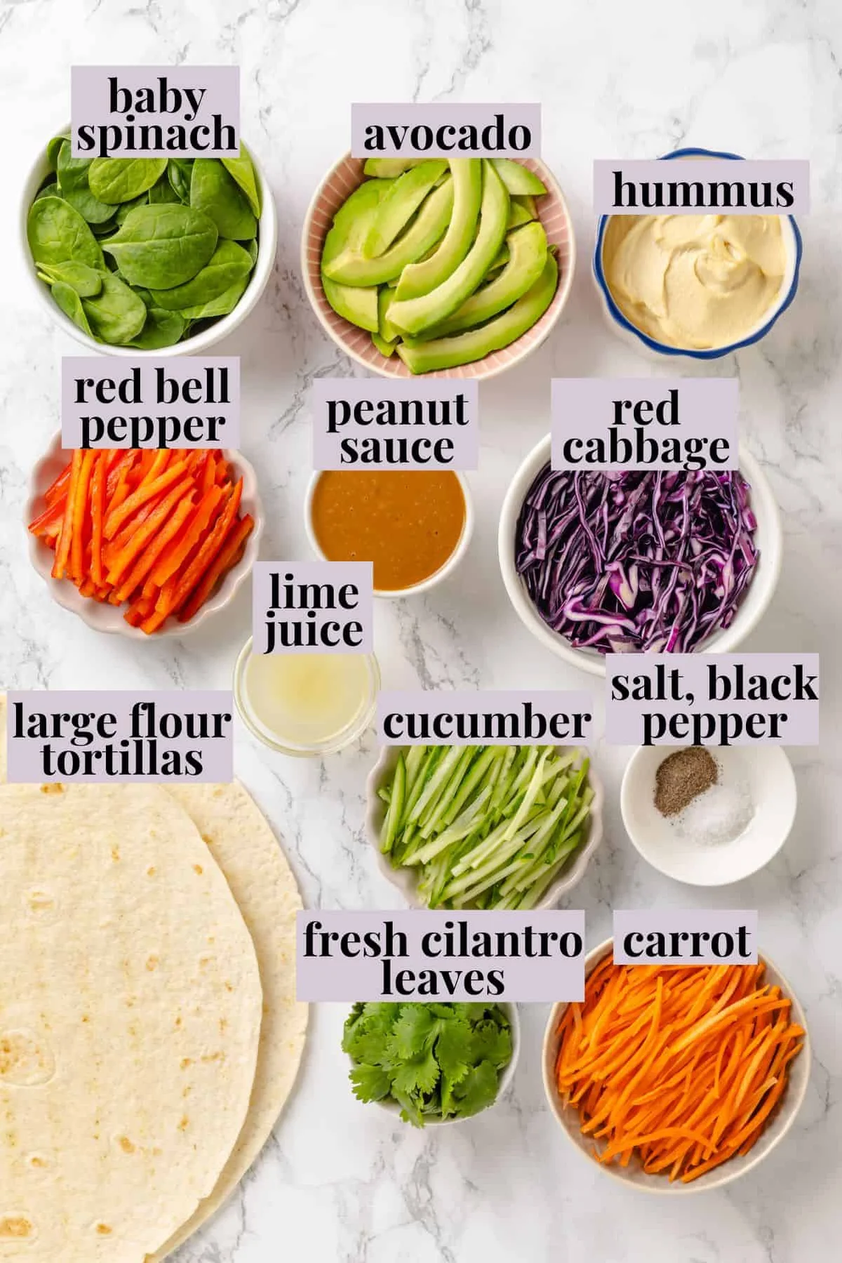 Labeled ingredients for veggie wraps: hummus, avocado, vegetables, lime and peanut sauce.