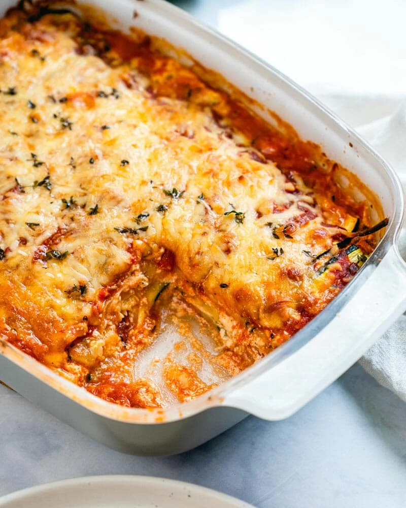 Baked lasagna with golden bubbly cheese top in a white ceramic dish