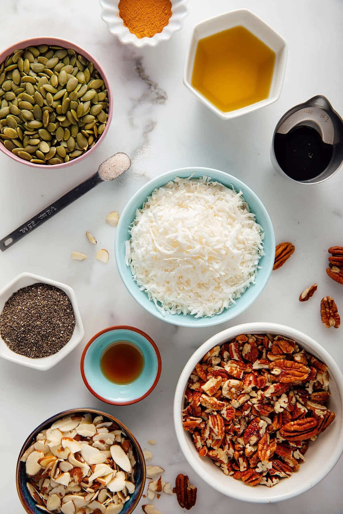 Nuts, coconut, pepitas, and spices arranged as recipe ingredients