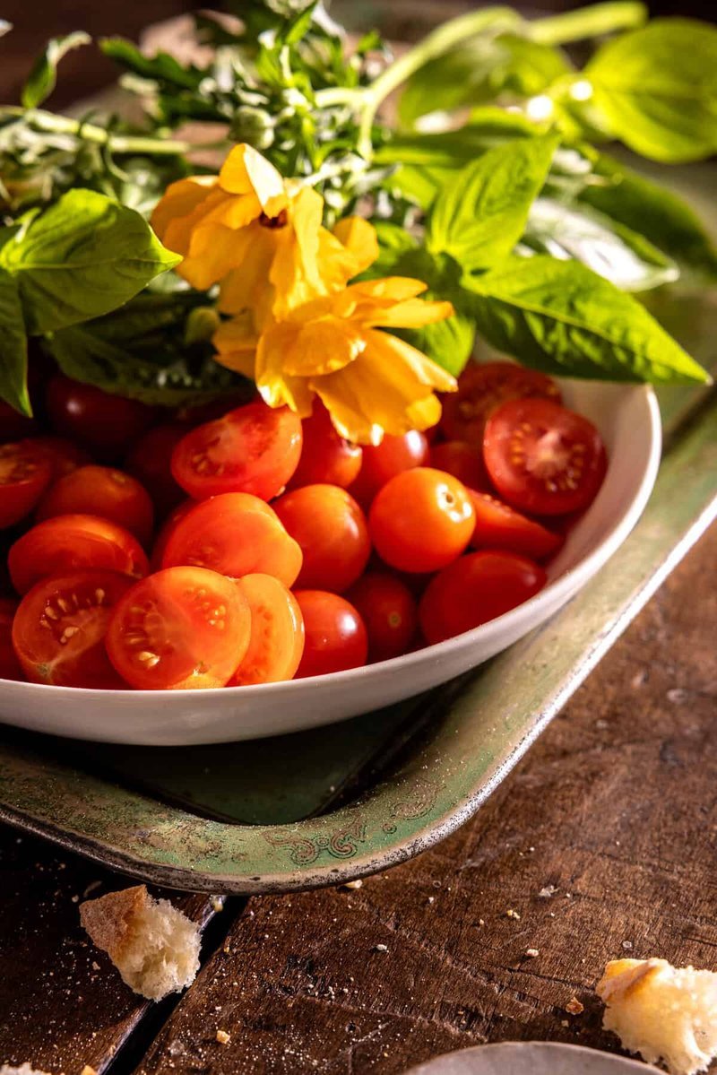Bowl of halved cherry tomatoes topped with fresh basil leaves