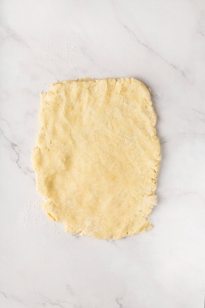 Rolled-out rectangular biscuit dough on floured surface